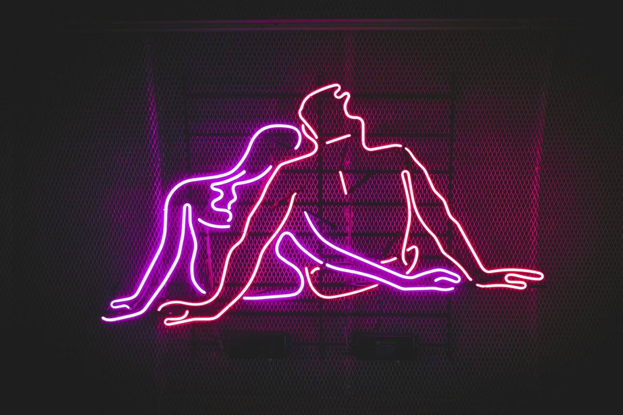 Letrero de neón de una pareja sensual, que ilustra el lifestyle swinger en datos