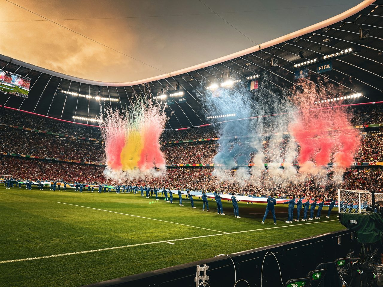 Estadio de fútbol de noche con bengalas y equipos formados, el Mundial 2026